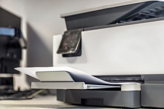 Laser printer with printed documents in output tray office workspace