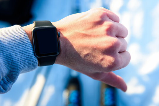 Skier checking fitness tracker while cross-country skiing in a snowy forest.