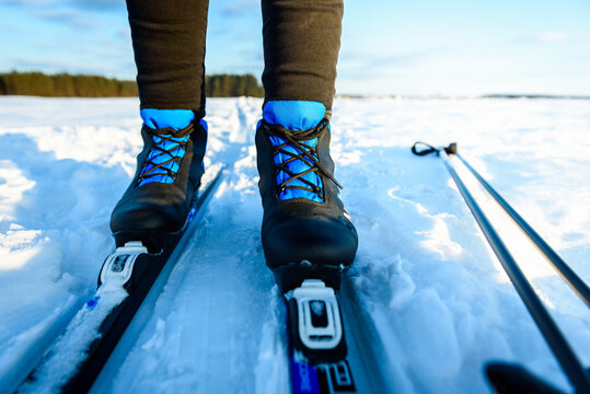 Skier on cross-country skis in the snow on forest trail of the sun above the horizon in winter.