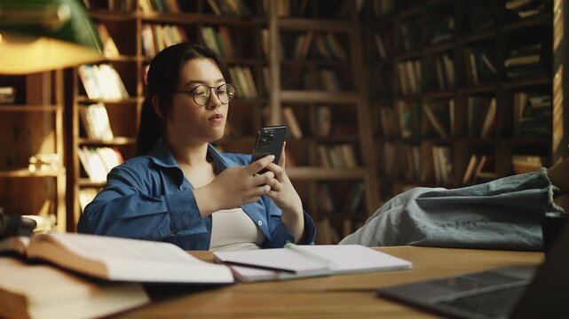 Asian woman student scrolling phone instead of studying, procrastination