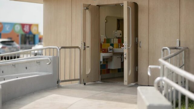 Medium shot focusing on a familyfriendly drivein restroom entrance featuring childsized facilities and colorful signage slightly blurred in the background.