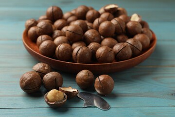 Obraz premium Macadamia nuts and metal key on light blue wooden table, closeup