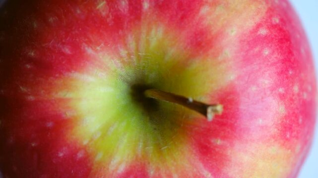 Delicious ripe red apple moving slowly downwards in beautiful macro view showcasing fresh skin, vibrant colors, healthy appeal against clean white background. Ripe red apple moving in detailed closeup