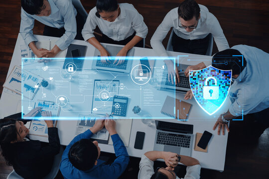 A professional business team collaborates in a modern office space, discussing cybersecurity strategies, while utilizing digital interfaces to protect their data and enhance productivity. Trope