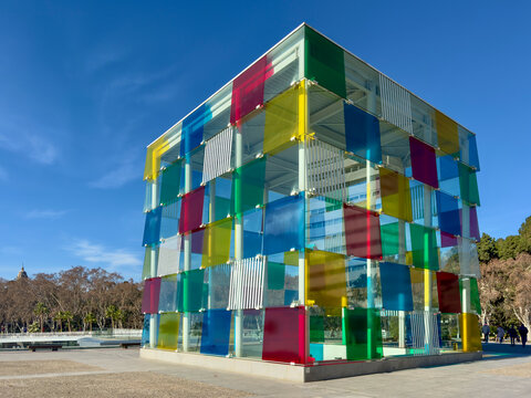 Malaga, Spain - January 19, 2026: Colourful glass cube of Centre Pompidou M&aacute;laga against clear blue sky, a contemporary architectural landmark in the Spanish port city, a vibrant urban design.