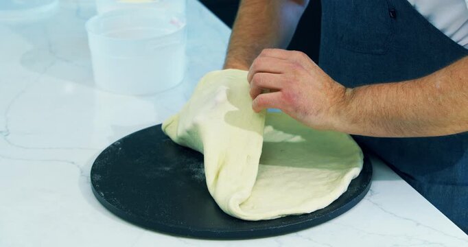 Cook checking out stretched out pizza dough - closeup shot
