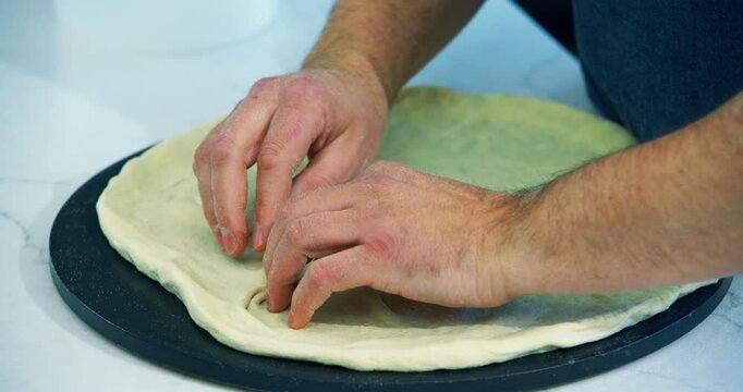 Cook patching up hole in stretched out pizza dough - closeup shot