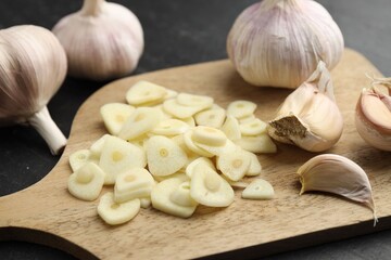 Cut garlic and bulbs on black table, closeup