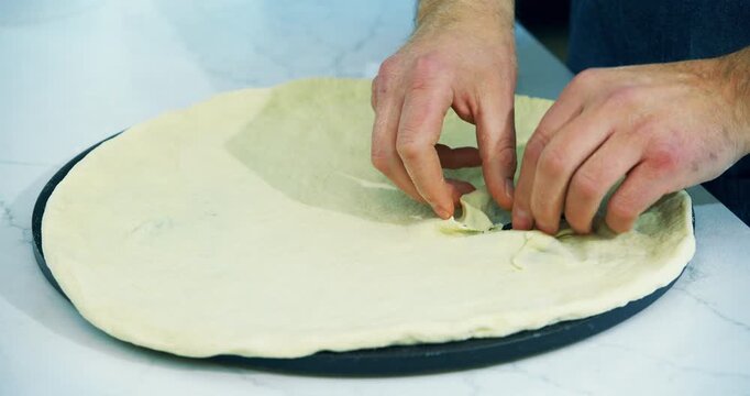 Cook tearing hole in pizza dough then patching it up with flour - closeup