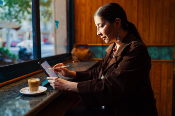 Confident woman using tablet with stylus, backlit by warm indoor light, embodying modern tech fluency, remote freedom, and the empowered rhythm of solo digital entrepreneurship. © BullRun