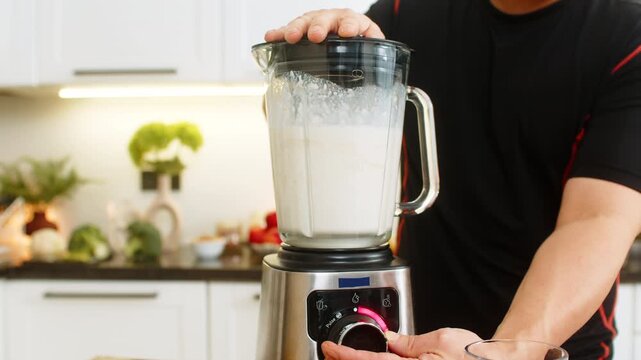 Man holds lid on blender mixing banana milk cottage cheese and whey protein into smooth shake. Protein smoothie serves as breakfast or post workout drink for support weight control body energy daily.