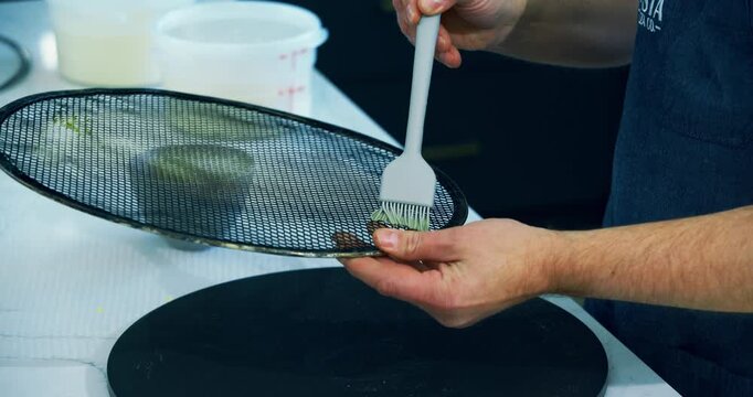 Cook using brush tool to spread oil on strainer