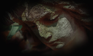 Naklejka premium Haunting sculpture close-up in greenish darkness, representing decay, sorrow, and hidden fear.
