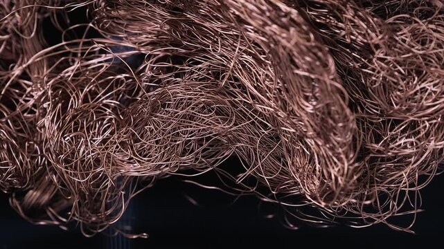 Thin, twisted, and chaotically tangled copper wire against the backdrop of an industrial interior, abstract metallic from non ferrous metals in a factory environment