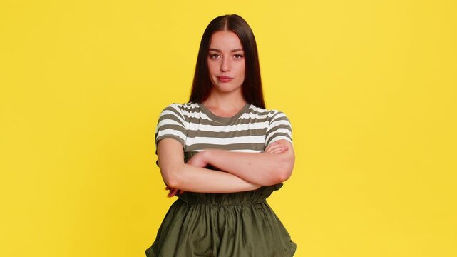 Young woman angrily waving finger and shaking head with disapproving expression clearly showing dissatisfaction and strong rejection. Girl on yellow background demonstrates emotional frustration anger