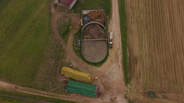 Aerial View of Agricultural Farm: An aerial perspective reveals a functioning farm with a biogas digester, storage silos, and surrounding agricultural fields.