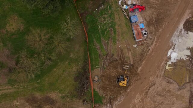 Flooded Landscape with Excavators: An aerial view reveals the devastating impact of flooding on a rural area, with muddy waters encroaching on fields and construction equipment.