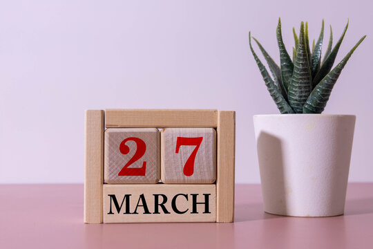 Minimalist green wooden block perpetual date calendar displaying MARCH 27 with light grey background