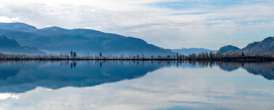 Canada, BC, Osoyoos.  Reflection of sky and trees lining the edge of lake in the Southern Okanagan Valley.
