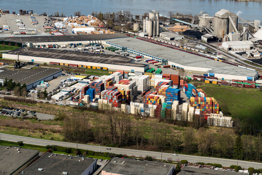 Canada, BC, Delta.  Aerial view of shipping container storage facility with a Cement factory in the background on the right.  On the banks of the Fraser River