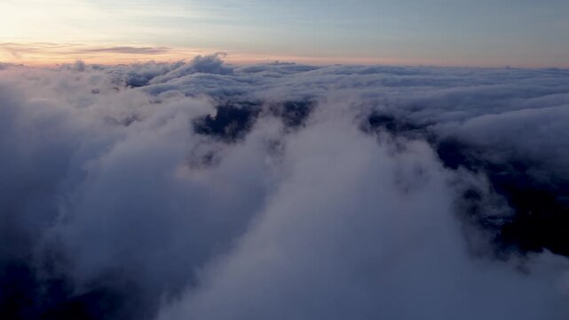 Aerial view of clouds float over valleys at sunrise