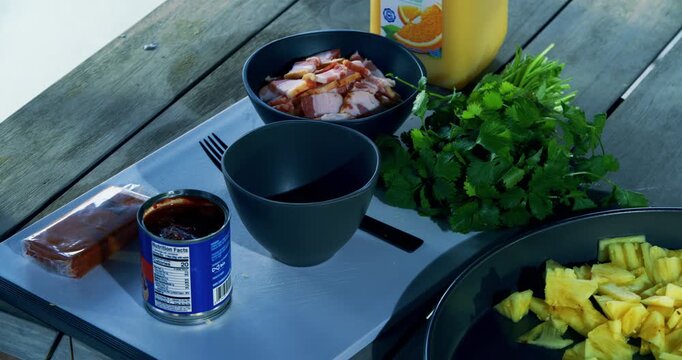 Hand taking bowl of raw meat on table with other toppings - high shot