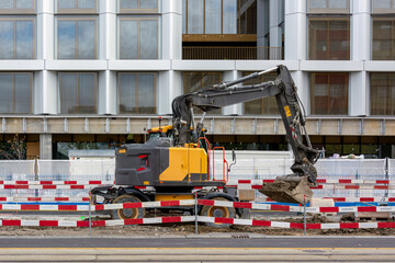 Obraz premium Excavator at urban construction site with safety barriers