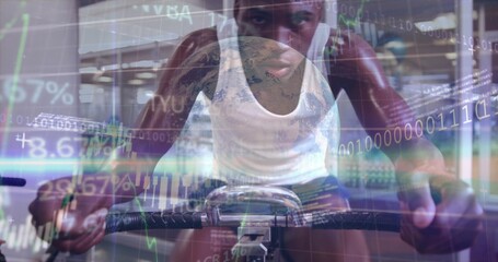 Pedaling athlete on exercise bike at gym, wearing white tank top, dark shorts with digital charts