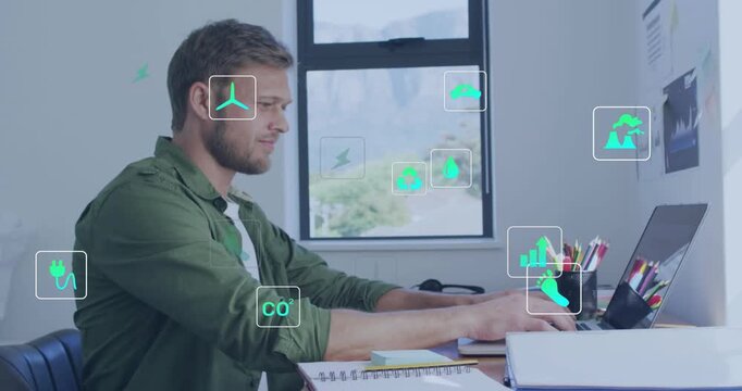 Man typing at laptop and reaching for pen, activating green energy icons while analyzing charts