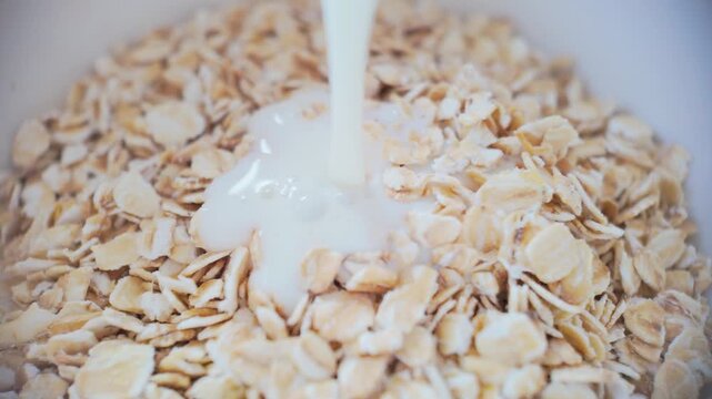 Close up slow motion milk pouring into oats, creamy texture forming healthy breakfast base
