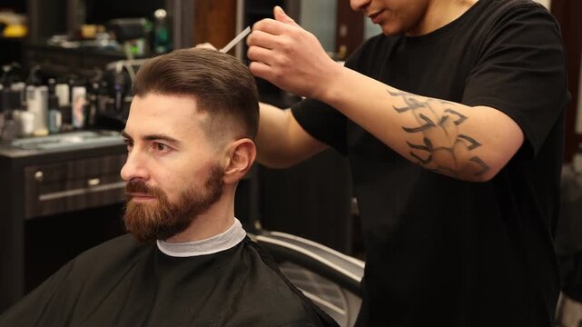 Stylist cutting man's hair with scissors in barbershop