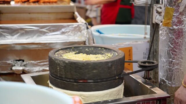 市場の屋台で緑豆を石臼で挽いているシーン