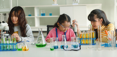 Three girls are in a science lab, working on an experiment