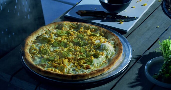 Cook putting steaming veggie pizza on large plate - closeup