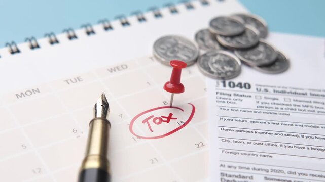 A close-up view of a calendar with a 'tax' reminder, a tax form, coins, and a pen, symbolizing the tax season and financial planning