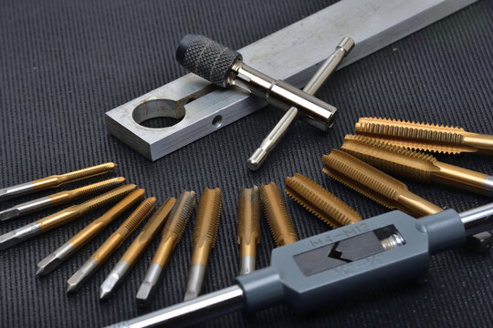 Threading tool in action on a aluminum piece. Tapping tool to create thread. Metal tap and drive handle. Hand threading tool.