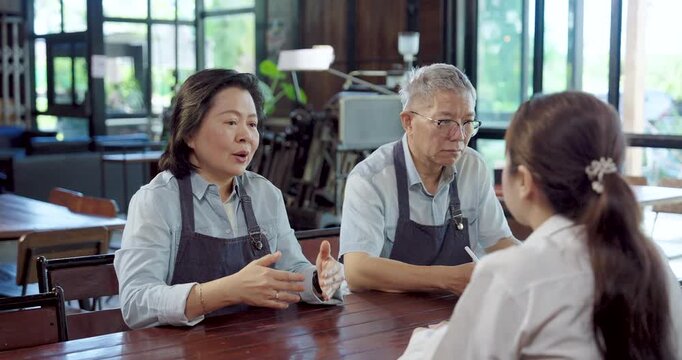 Senior asian entrepreneurs smile while coaching barista team, husband wife motivate employees, create positive workplace culture, teamwork communication improve service quality for small cafe business