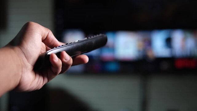 Person using remote control to browse streaming platform on smart television at home
