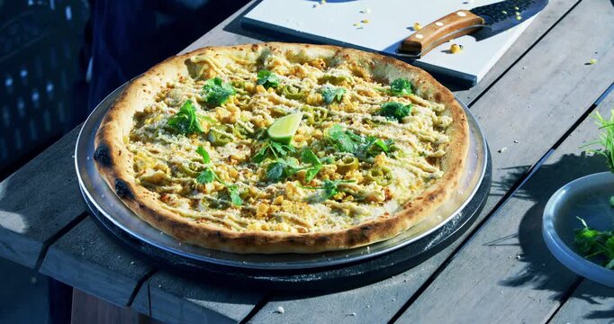 Closeup on veggie pizza with lime being cut with roller by chef