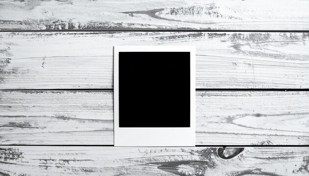 Instant photo frame on wooden background. Whitewashed wood texture. Black and white polaroid frame. Blank instant photo. Wooden planks. Gray wooden surface. Horizontal wood grain. Photo