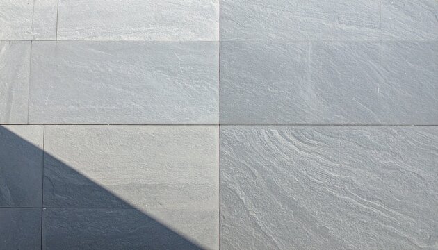 Large gray stone or marble tiles with shadow on a floor or wall surface