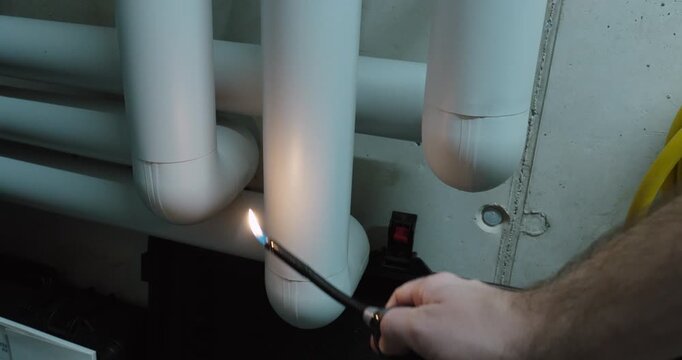 Close-up of a flame held directly against insulated pipes in a utility room, demonstrating fire resistance testing, material durability and industrial safety standards.