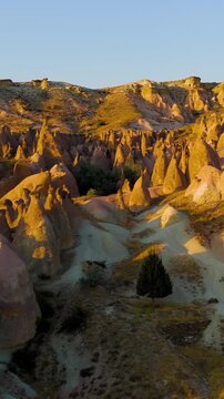 Vertical video. Goreme, Nevsehir, Turkey. Evening aerial view of Devrent Valley colorful rock formations and whimsical erosion patterns in Cappadocia during sunset.. Aerial View. Rich colors