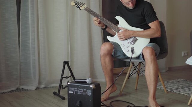 Electric guitar string instrument video. Man playing nylon strings during music self-teaching lessons in living room. Musical education and art people concept