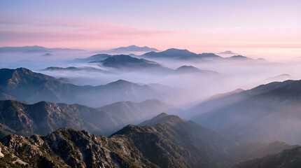 Fototapeta premium Misty Mountain Layers at Sunrise with Soft Pastel Sky