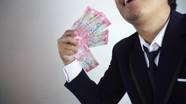 Close up of a man fanning rupiah money in front of his face. Copy space, Promotion, Marketing