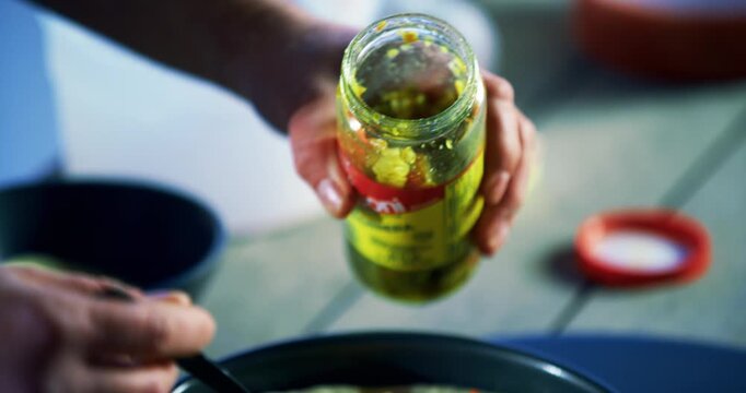 Closeup of cook putting peppers on dish with meat and pizza dough inside