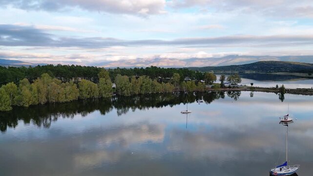 Aerial view of anchored boats resting on a reservoir in Extremadura, Spain. Wide natural landscape with calm inland waters and rural surroundings.
