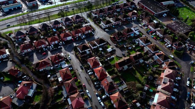 aerial drone shot high angle over the Millbrook suburban housing area estate in Southampton at sunset with trees, homes and nature surrounding. Shot in winter with traffic and cars driving the streets