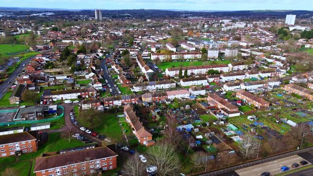 aerial drone shot high angle over the Millbrook suburban housing area estate in Southampton at sunset with trees, homes and nature surrounding. Shot in winter with traffic and cars driving the streets
